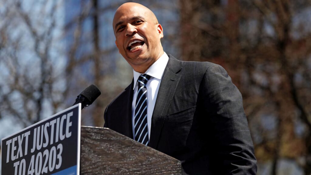 Cory Booker speaking at podium outdoors about criminal justice reform with sunlight background Wallpaper