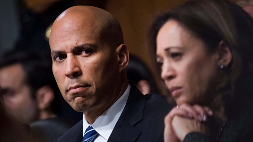 Cory Booker attentively listens at committee hearing with serious expression in formal setting Wallpaper