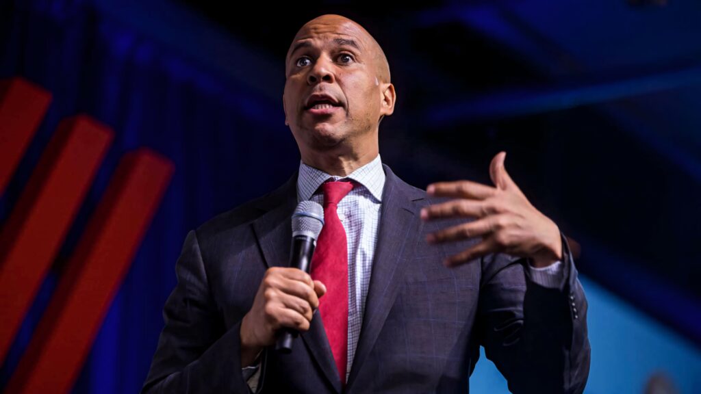 Cory Booker speaking passionately on women rights with bold lighting and blue red tones wallpaper