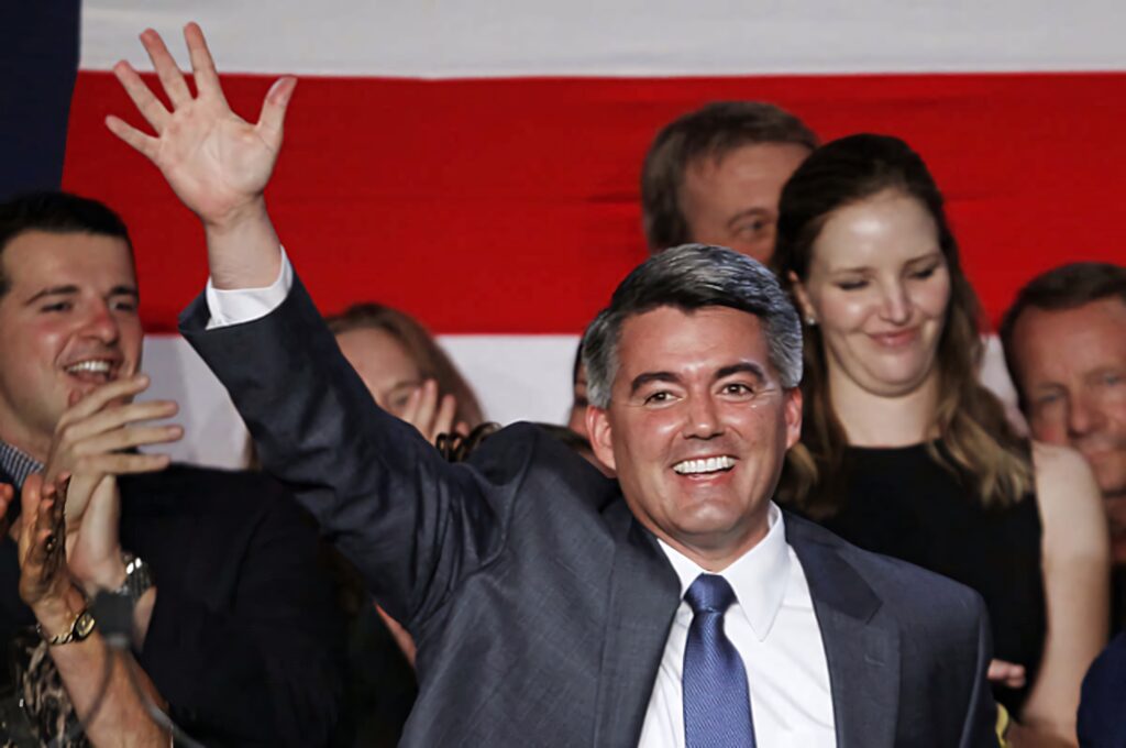 Cory Gardner smiling and waving at crowd with large American flag patriotic event background Wallpaper