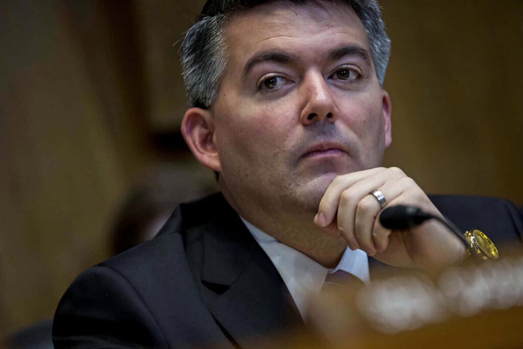 Cory Gardner in dark suit and tie with thoughtful expression blurred formal background wallpaper