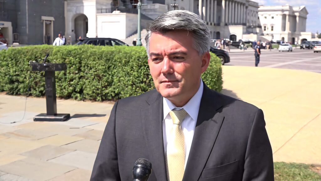 Cory Gardner in dark suit and yellow tie outdoors near government building under clear sky wallpaper