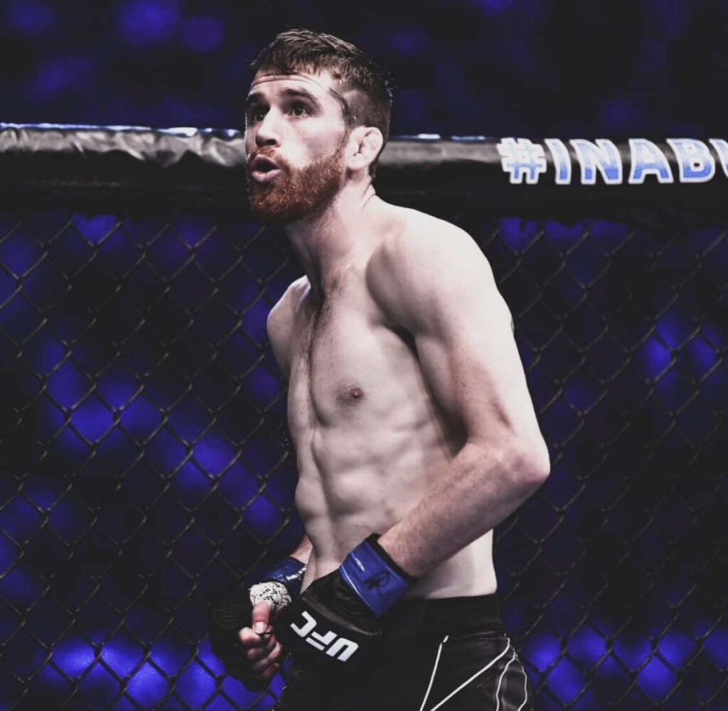 Cory Sandhagen in UFC Octagon with blue lighting showing intense focus and athletic physique Wallpaper