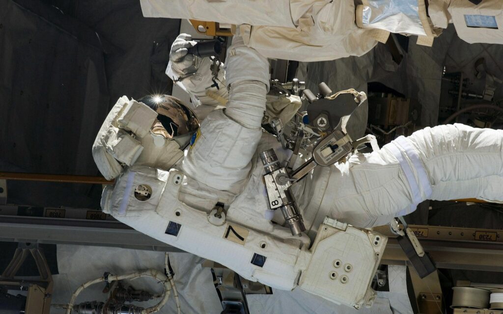 Space Wallpaper: Cosmonaut Repairing Spacecraft in Survival Suit