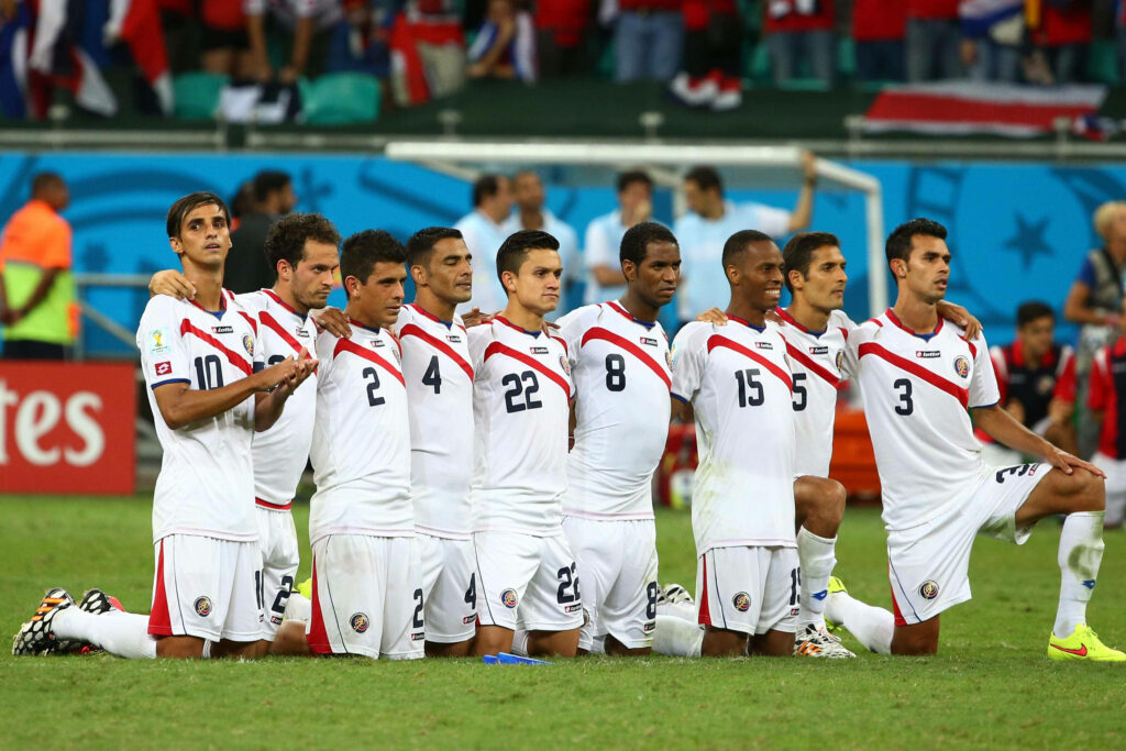 Costa Rica National Football Team lineup in white and red kits kneeling on green pitch united Wallpaper