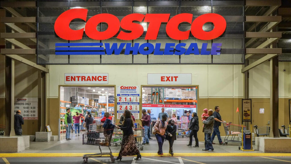 Front view of Costco Wholesale store with bold red blue signs busy shoppers carts bright lighting Wallpaper