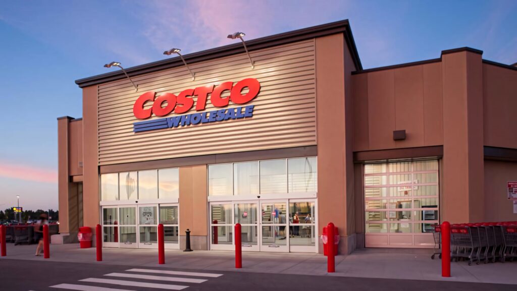 Costco Wholesale store exterior at sunset with red blue signs beige walls and shopping carts lined up Wallpaper