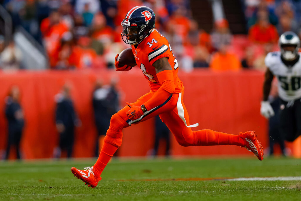 Courtland Sutton in orange Denver Broncos uniform runs on field during intense football game action Wallpaper
