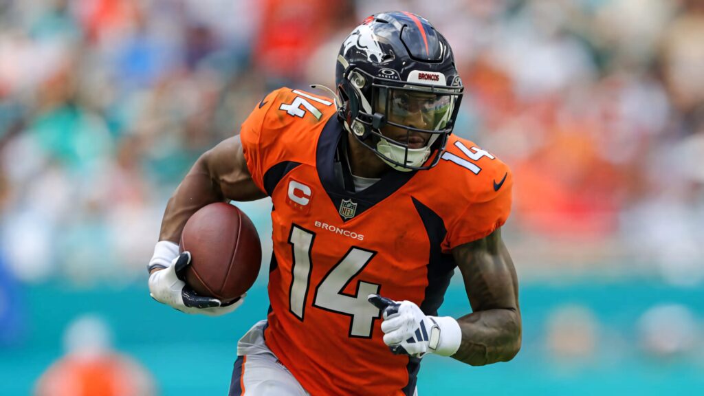 Courtland Sutton Denver Broncos number 14 charges forward gripping football in vibrant game action Wallpaper