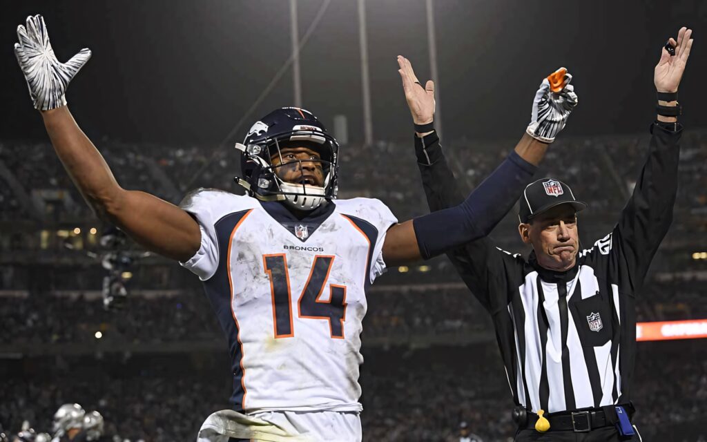 Courtland Sutton Denver Broncos celebrates touchdown with NFL referee under bright stadium lights Wallpaper