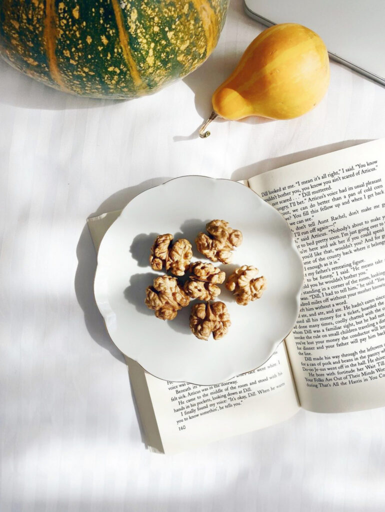 Cozy Aesthetic: Walnuts, Book & Pumpkins on Textured Surface Wallpaper