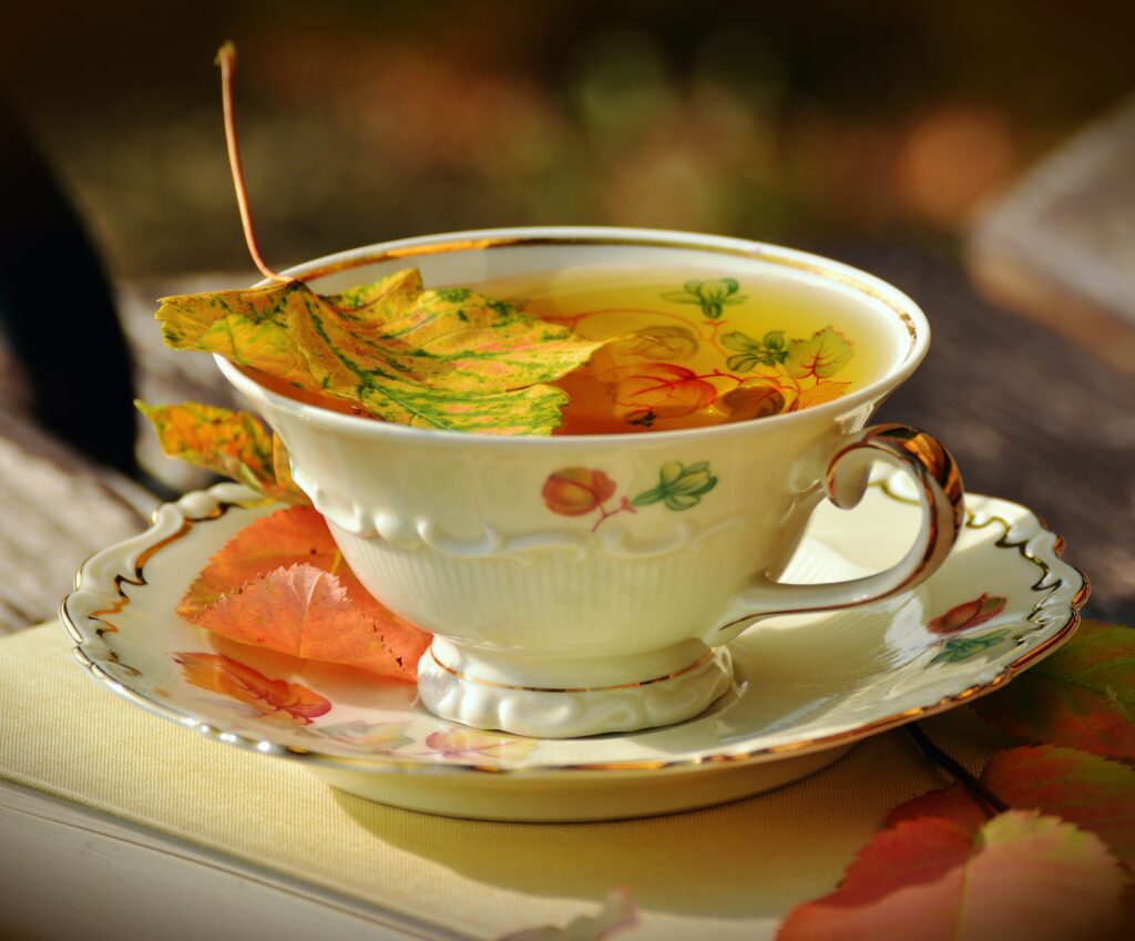 Cozy Autumn Teacup with Vibrant Leaves - Warm Wallpaper Background