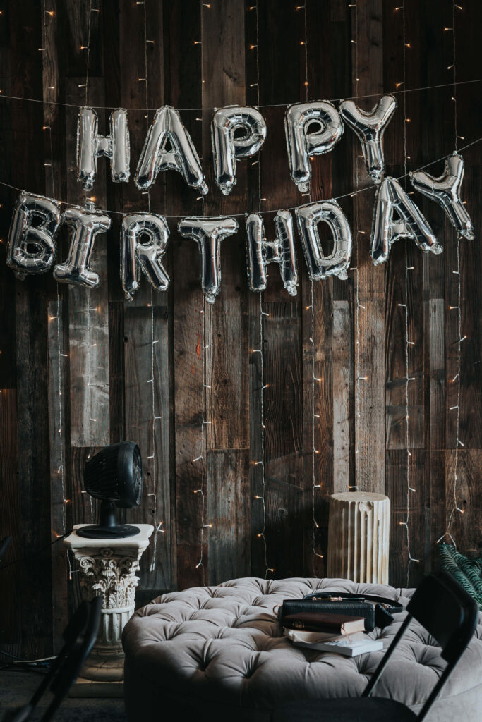 Cozy Birthday Scene: Metallic Balloons & Rustic Charm with Fairy Lights Wallpaper