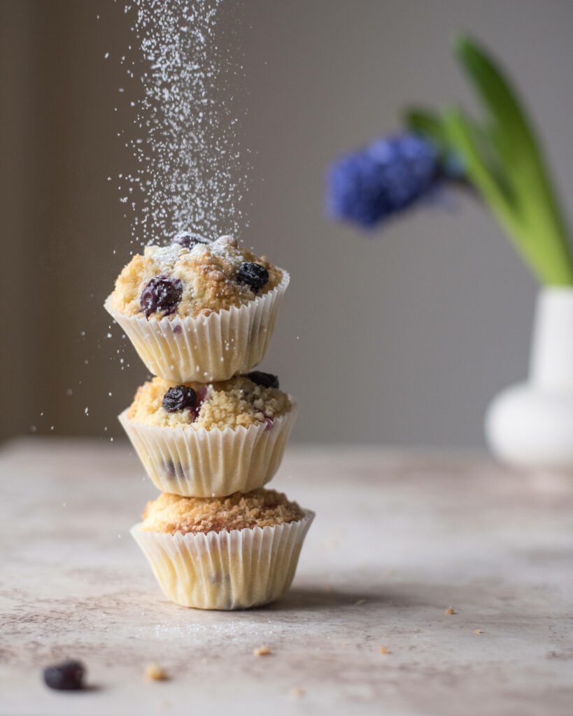 Stack of three blueberry muffins with powdered sugar and warm natural lighting background Wallpaper
