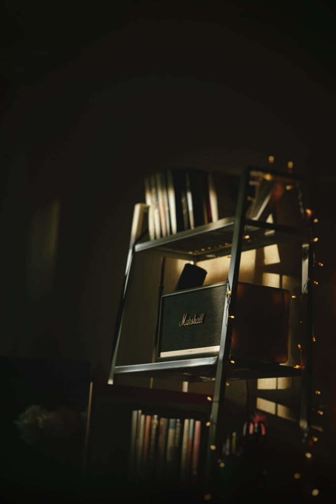 Cozy personal bookshelf with warm string lights in dim room perfect for reading and relaxation Wallpaper