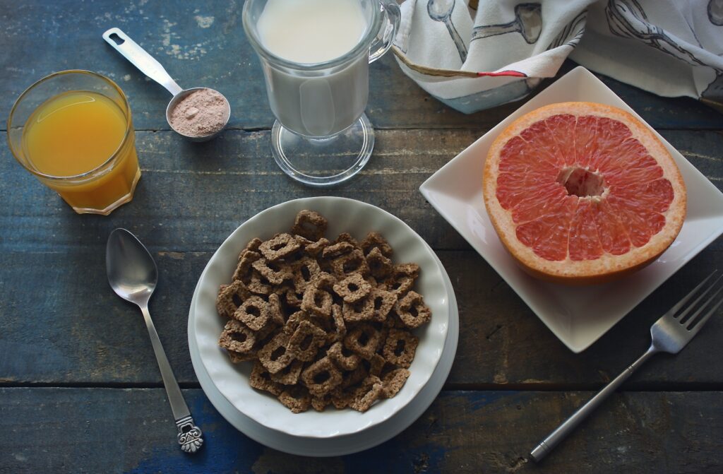 Cozy Breakfast Setup: Cereal, Grapefruit & Juices on Rustic Table Wallpaper