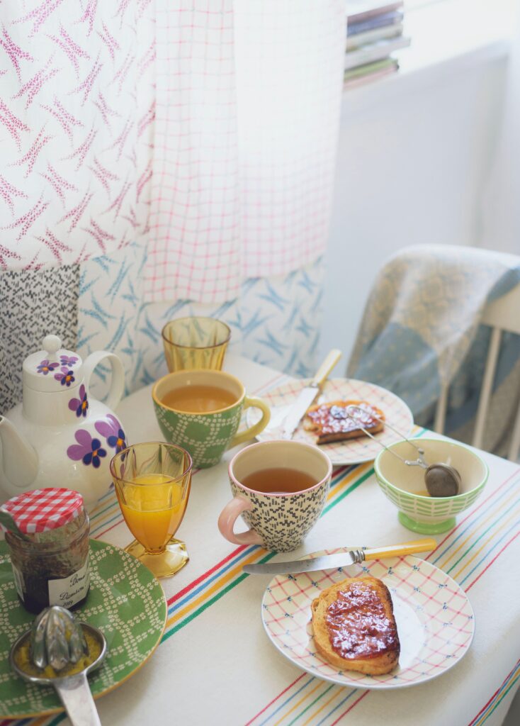 Charming Tea Party Ambiance: Cozy Breakfast Setup with Vibrant Dishware Wallpaper