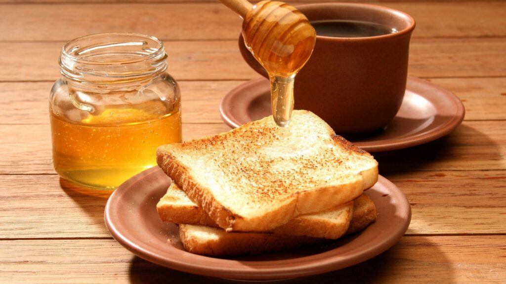 Cozy Breakfast Bliss: Toasts & Honey with Tea on Wooden Table Wallpaper