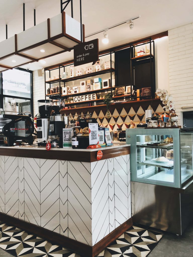 Cozy modern cafe counter with chevron tiles pastries display and professional coffee equipment background Wallpaper