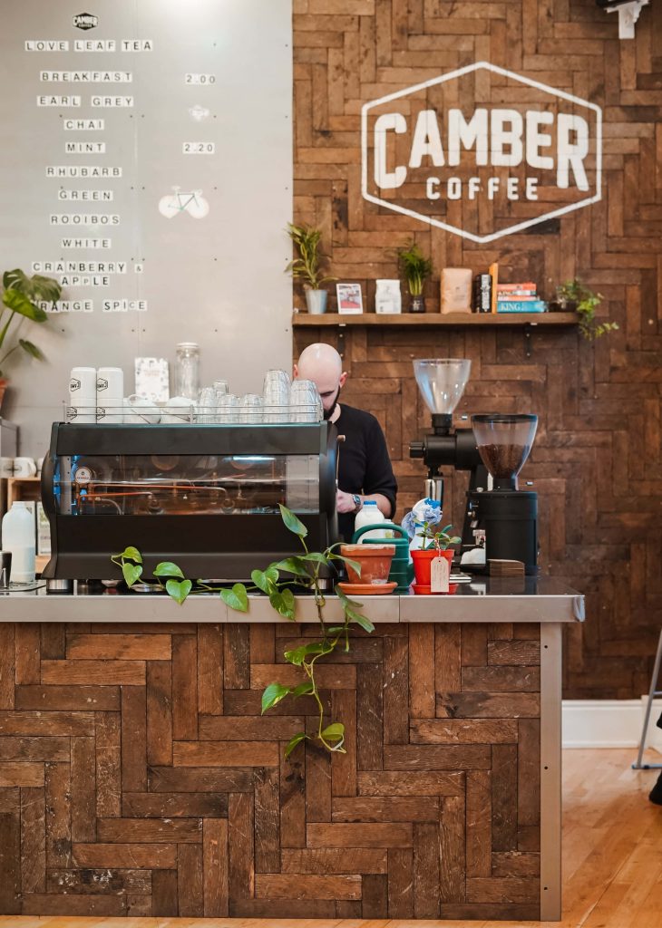 Cozy Camber Coffee shop wallpaper with rustic wood counter espresso machine and indoor greenery