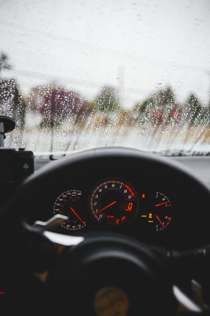 Cozy Car Interior: Steering Wheel & Speedometer with Raindrops Wallpaper