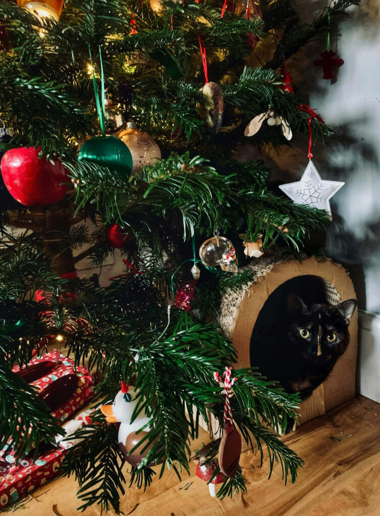 Cozy Cat Peeks from Christmas Tree: Festive Holiday Scene Wallpaper