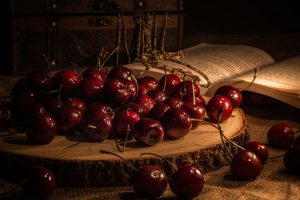 Cozy cherry wallpaper with glossy ripe cherries on rustic wood and vintage book in warm light