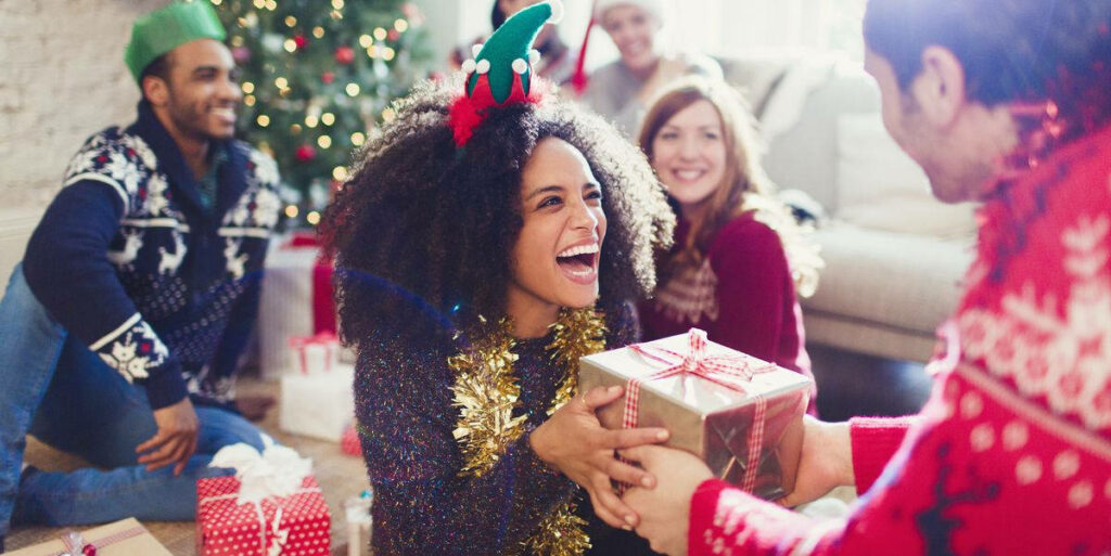Joyful Friends Exchanging Holiday Gifts in a Cozy Christmas Living Room Wallpaper