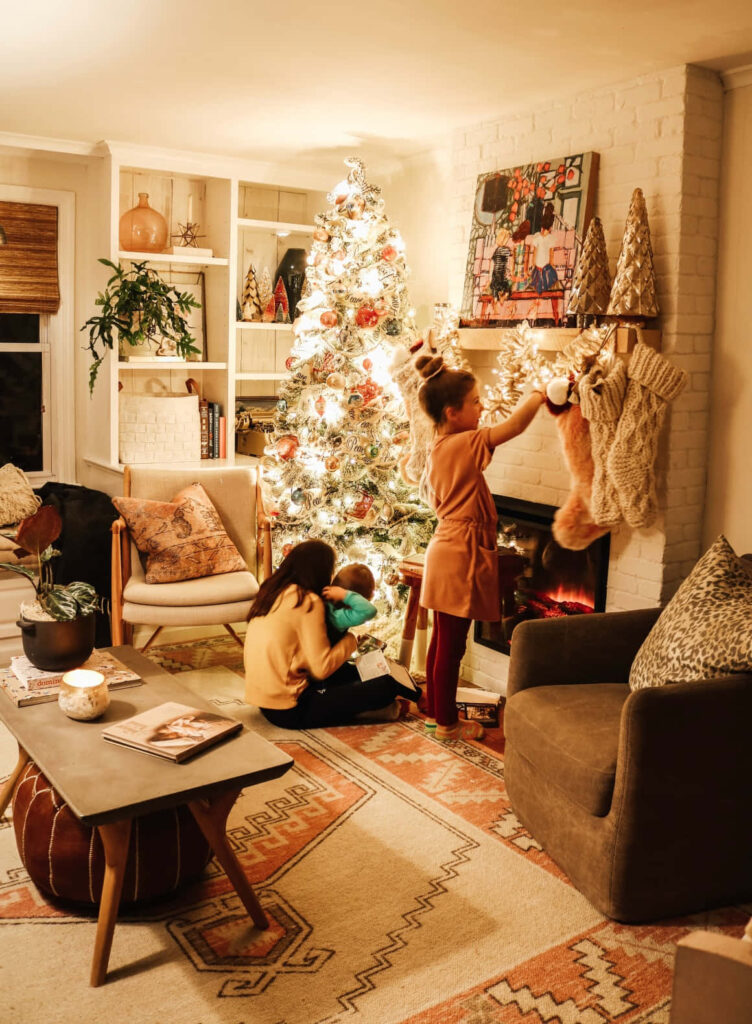 Cozy Christmas Living Room with Family & Beautifully Lit Tree Wallpaper