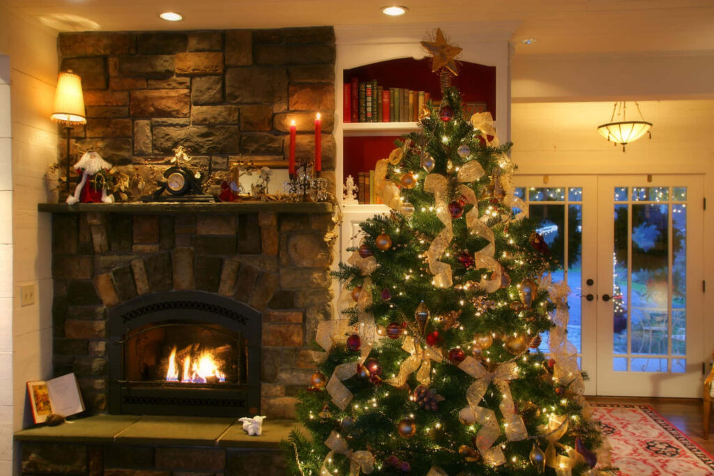 Cozy Christmas Scene: Warm Fireplace & Festively Adorned Tree Wallpaper
