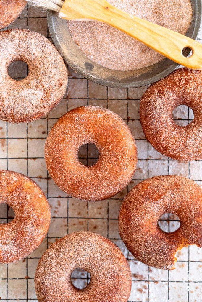 Golden brown cinnamon sugar donuts on cooling rack with soft fluffy texture warm tones wallpaper