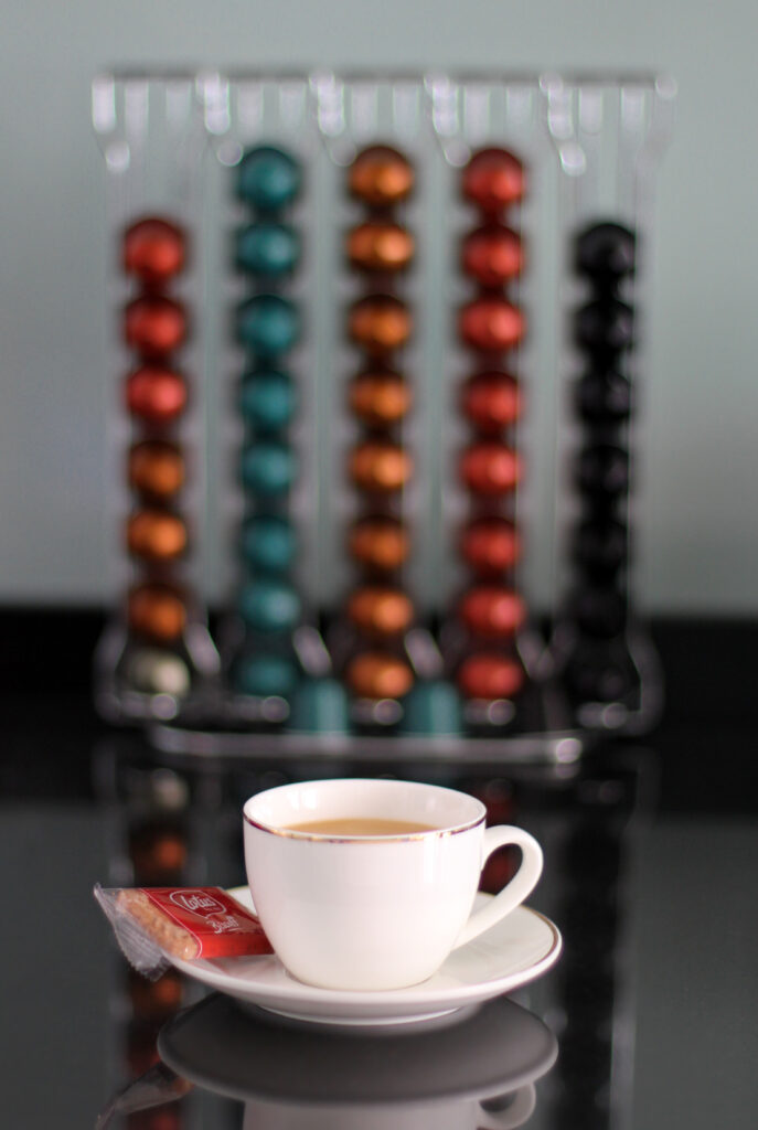Cozy Coffee Setup: Cup, Saucer, Cookie & Colorful Capsules Wallpaper