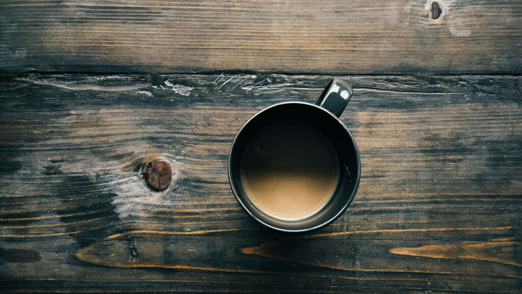 Warm coffee cup on rustic wood with earthy tones cozy inviting serene wallpaper background