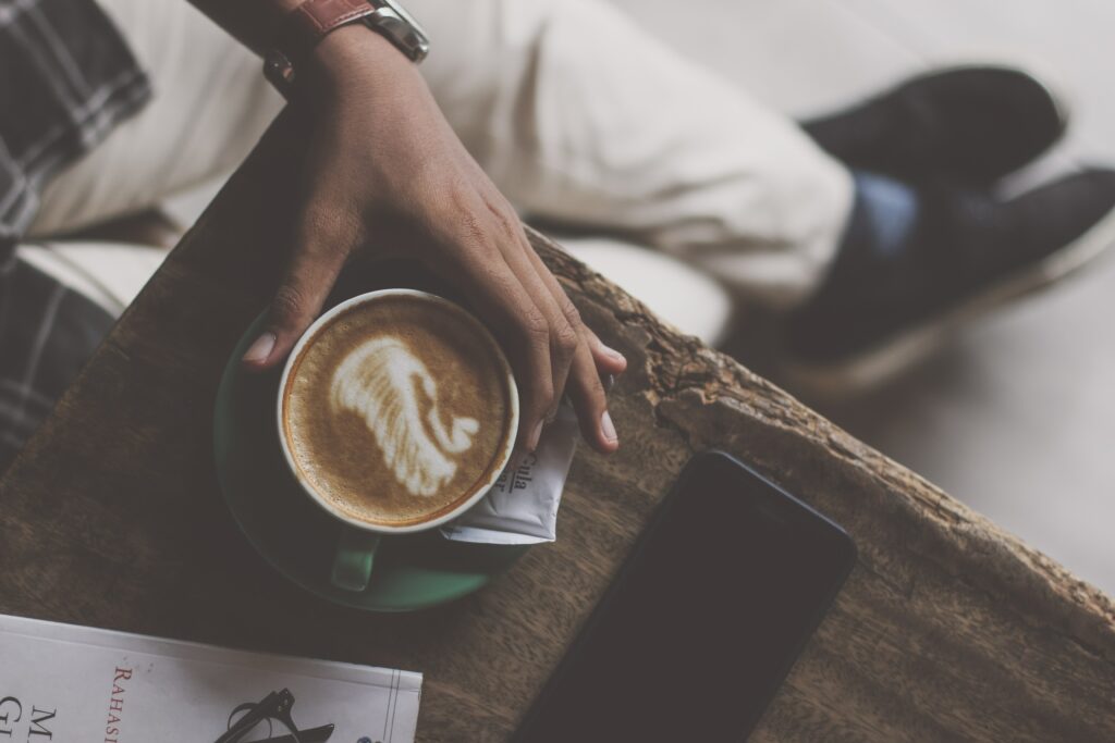 Cozy Coffee Moment: Hand, Latte Art, Book & Smartphone Wallpaper