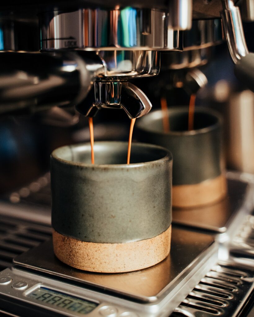Cozy Coffee Scene: Modern Machine Brewing Espresso in Rustic Cups Wallpaper