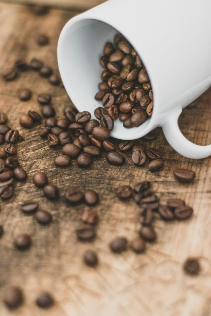 Rustic Coffee Scene: White Cup Spills Beans on Wooden Wallpaper
