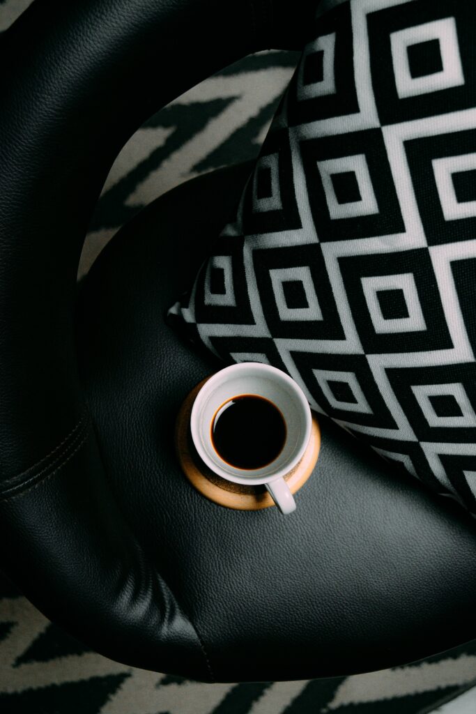 Cozy Coffee Moment: Black Chair & Patterned Pillow in Warm Atmosphere Wallpaper