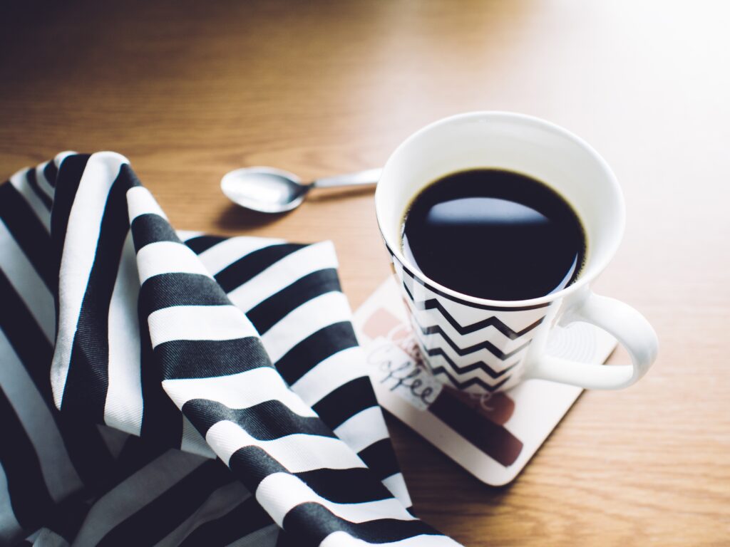 Cozy Coffee Setup: Black Coffee, Cozy Coaster & Towel on Wood Wallpaper