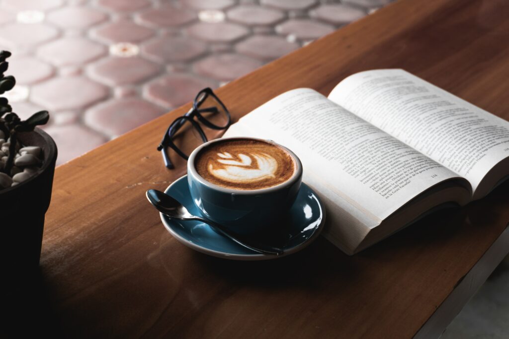 Cozy Coffee Setup: Steaming Cup, Open Book & Glasses on Wood Wallpaper
