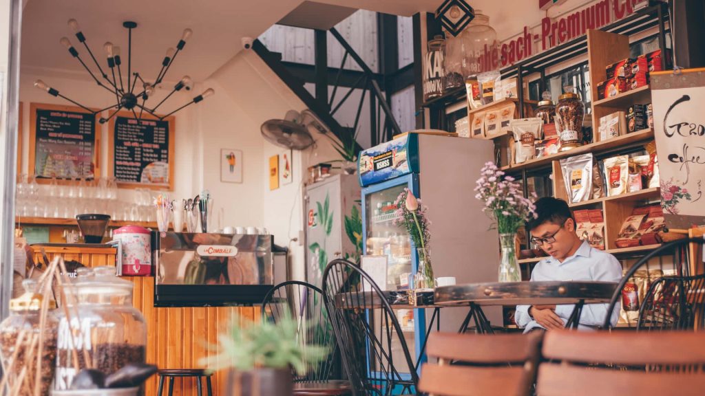 Cozy coffee shop interior with rustic shelves coffee bags La Cimbali espresso machine and fresh flowers Wallpaper
