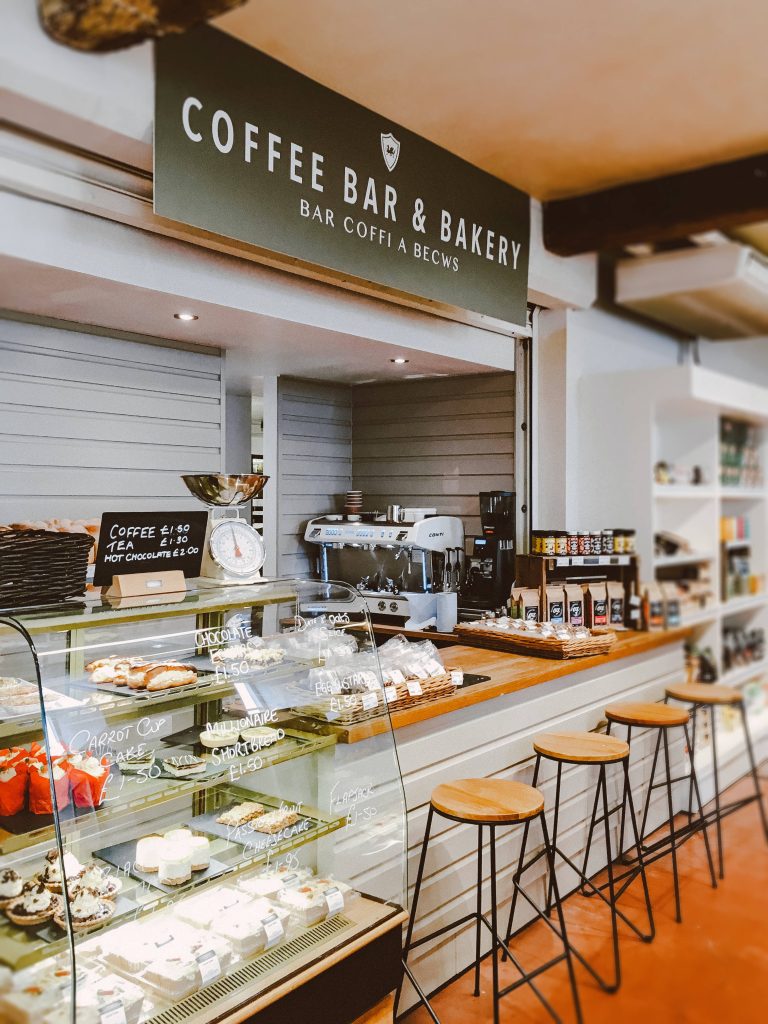 Cozy bakery counter wallpaper with glass pastry display warm wood modern stools and bilingual sign