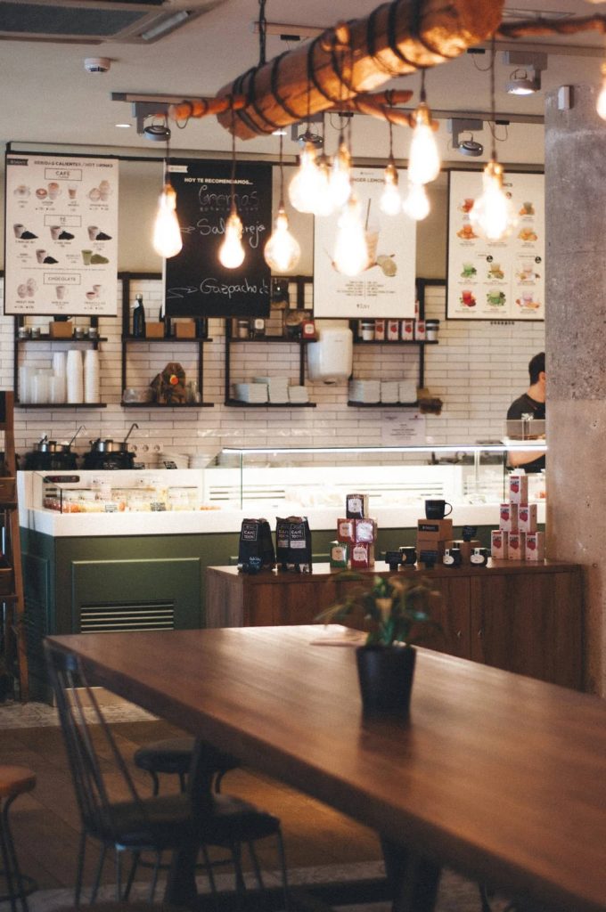 Cozy coffee shop wallpaper with Edison bulbs over rustic table and modern cafe interior