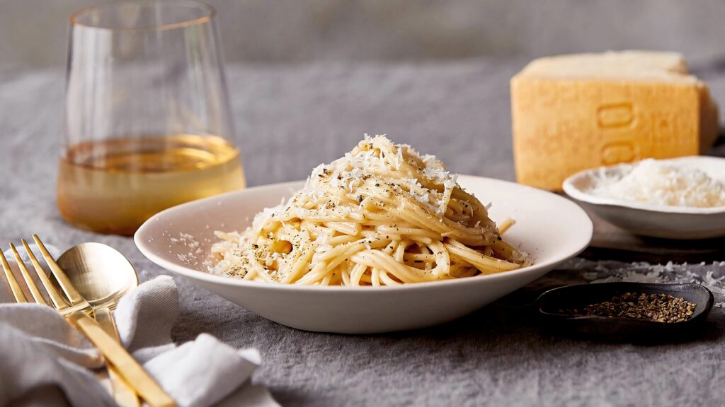 Creamy cacio e pepe pasta with cracked pepper and white wine in elegant cozy table setting Wallpaper