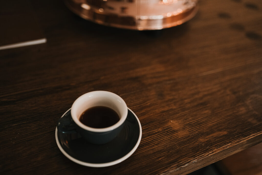 Cozy Espresso Wallpaper: Rustic Table with Dark Cup & Saucer
