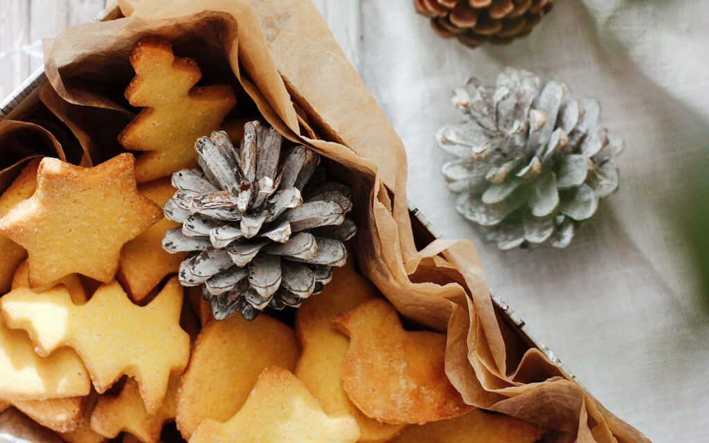 Cozy festive wallpaper with golden star tree bird cookies and frosted pinecones in warm tones
