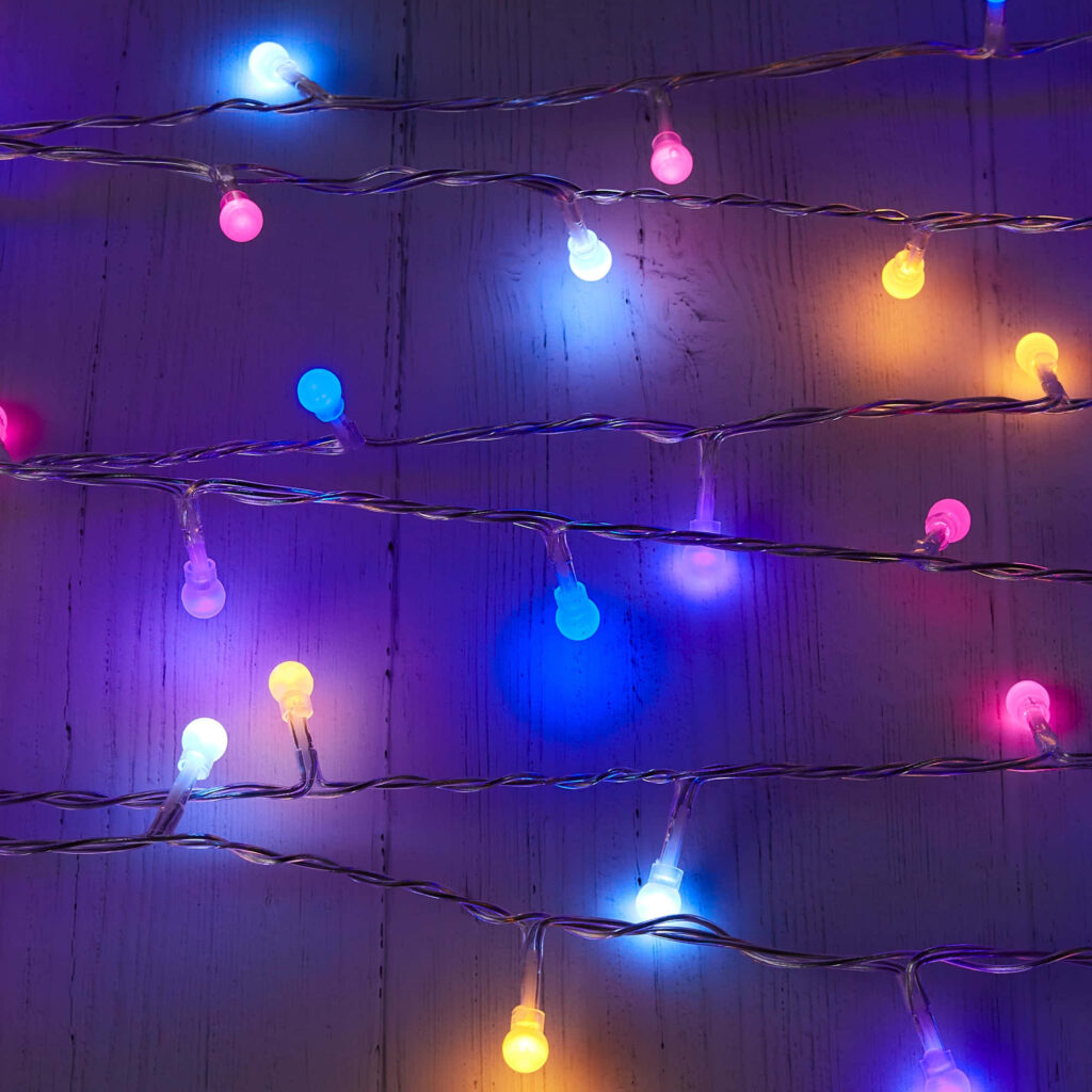 Vibrant multicolored string lights glowing on rustic wooden background festive cozy atmosphere Wallpaper