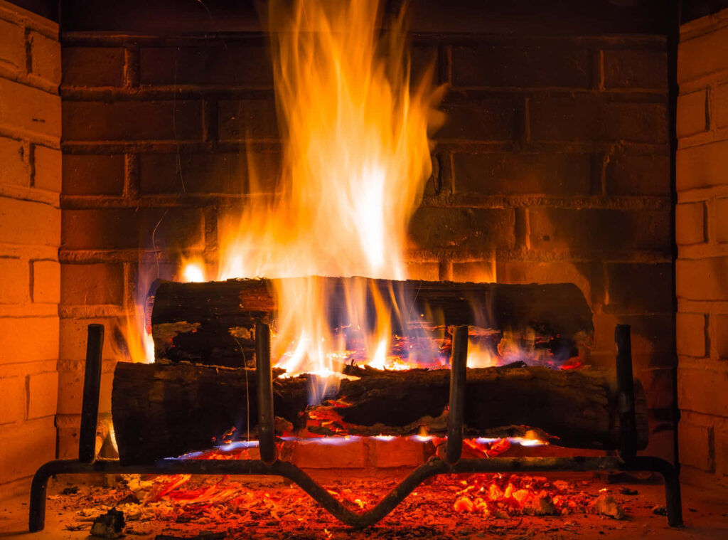 Cozy glowing fireplace with bright flames and rustic brick backdrop creating warm ambiance Wallpaper