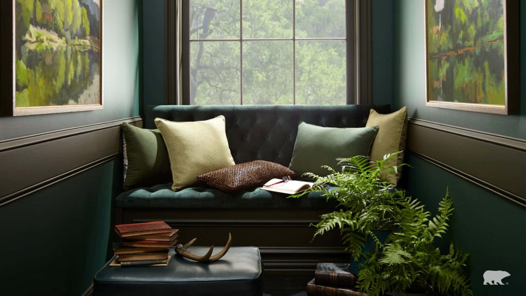 Cozy reading nook with green velvet seat stacked books ferns green wall window virtual background Wallpaper