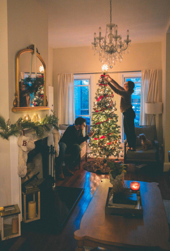 Festive Living Room: Couples Decorate Christmas Tree with Cozy Touches Wallpaper