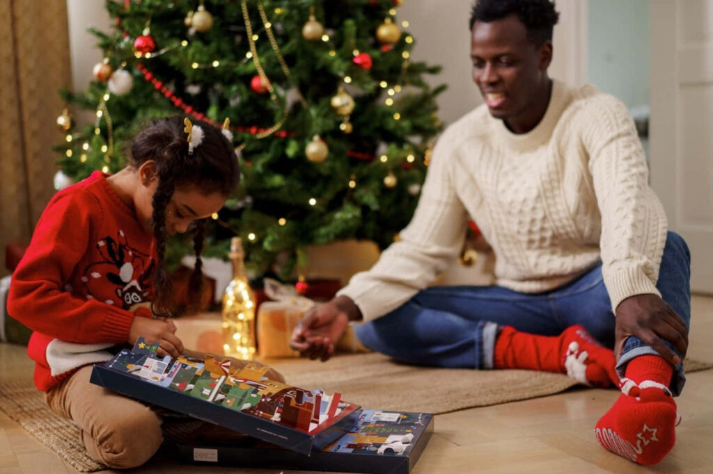 Cozy Christmas Scene: Girl Puzzling, Smiling Man by Festive Tree Wallpaper